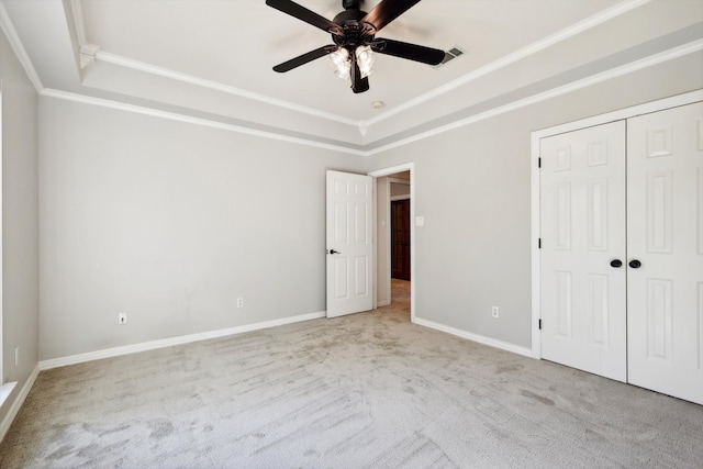 unfurnished bedroom featuring light carpet, a closet, a raised ceiling, and ceiling fan