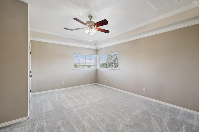 empty room with a raised ceiling, crown molding, ceiling fan, and light colored carpet