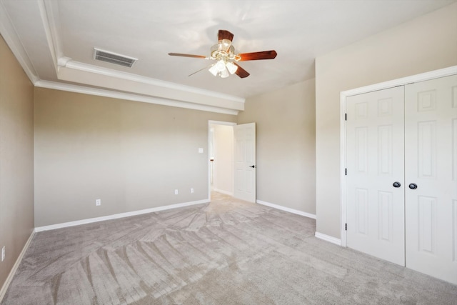 unfurnished bedroom with a closet, light colored carpet, ceiling fan, and ornamental molding