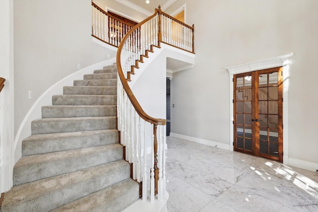 stairs with french doors, a towering ceiling, and ornamental molding