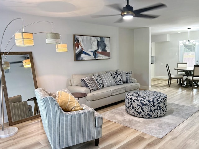 living room featuring light hardwood / wood-style flooring and ceiling fan with notable chandelier