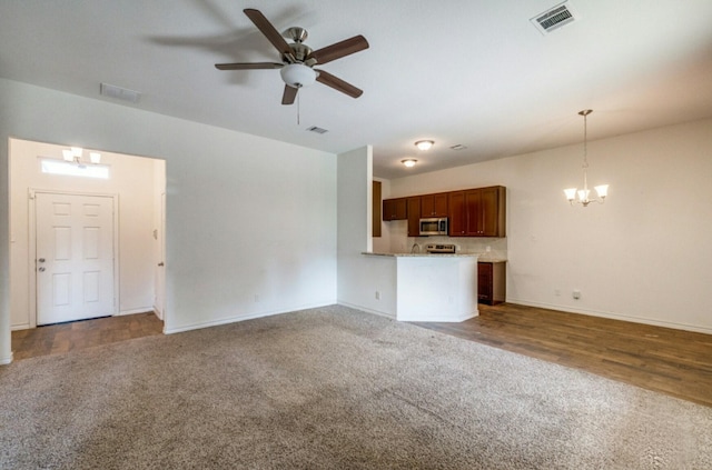 unfurnished living room with ceiling fan with notable chandelier and carpet floors