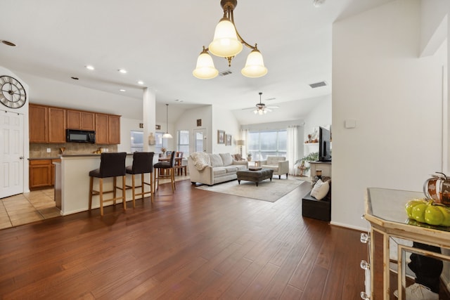 living room with wood-type flooring and ceiling fan with notable chandelier