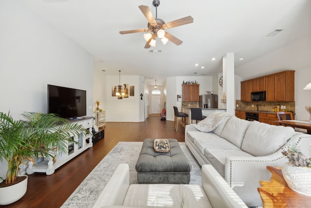 living room featuring ceiling fan with notable chandelier and dark hardwood / wood-style floors