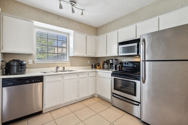 kitchen featuring light tile patterned flooring, white cabinetry, sink, and appliances with stainless steel finishes