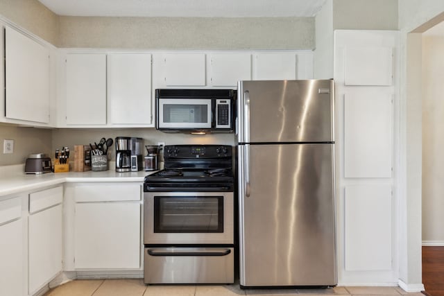 kitchen with white cabinetry, stainless steel appliances, and light tile patterned floors