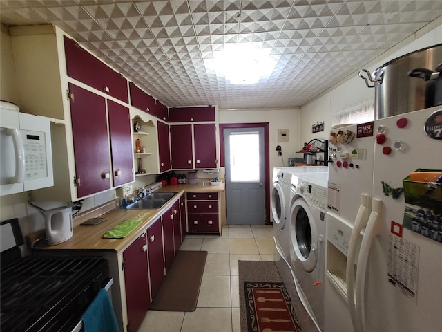 clothes washing area featuring washing machine and clothes dryer, light tile patterned floors, and sink