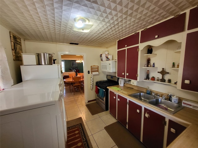 kitchen featuring independent washer and dryer, sink, light tile patterned floors, and stainless steel gas range