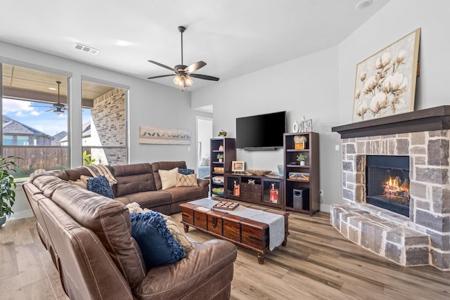 living room featuring light hardwood / wood-style flooring, a fireplace, and ceiling fan