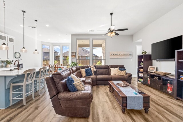 living room featuring ceiling fan, sink, and light hardwood / wood-style flooring