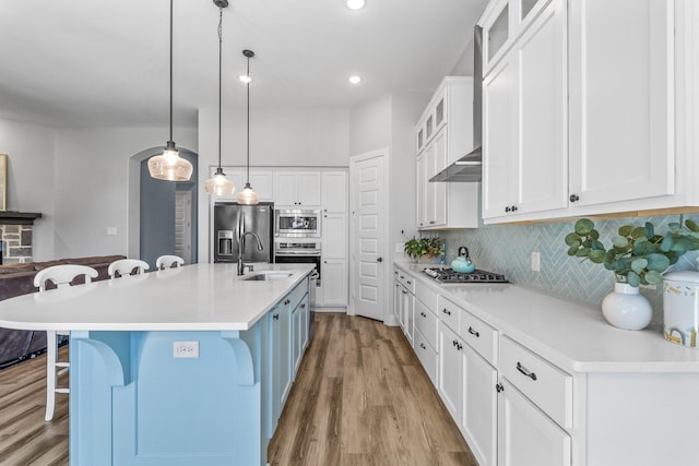 kitchen with white cabinetry, a kitchen bar, decorative light fixtures, and a center island with sink