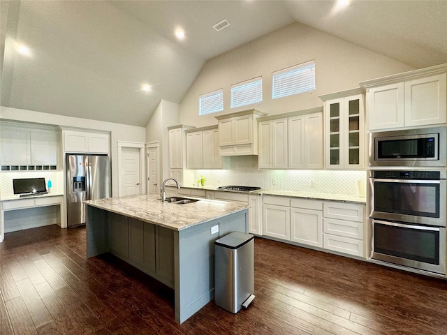 kitchen featuring appliances with stainless steel finishes, light stone counters, dark hardwood / wood-style floors, and an island with sink