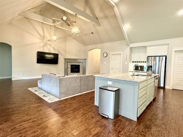 kitchen with beam ceiling, sink, a kitchen island with sink, and white cabinetry