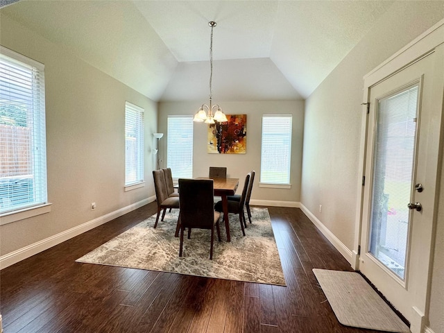 dining area with dark wood-type flooring, vaulted ceiling, and a chandelier