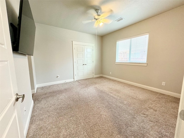 unfurnished bedroom with a closet, light colored carpet, and ceiling fan