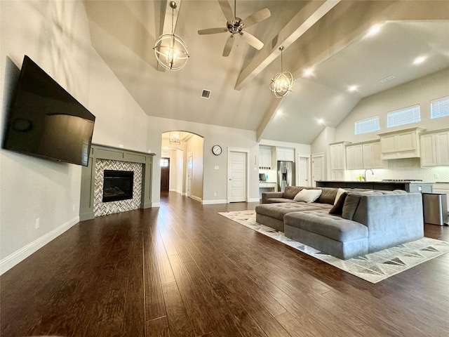 unfurnished living room with sink, a fireplace, ceiling fan, dark wood-type flooring, and high vaulted ceiling