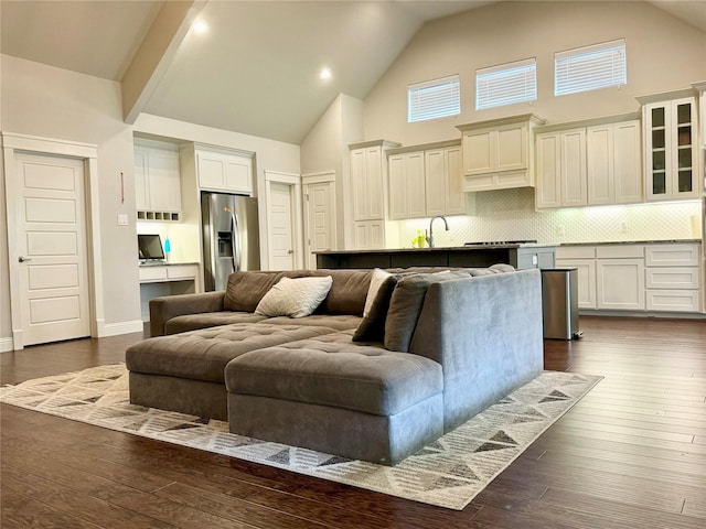 living room featuring beamed ceiling, dark hardwood / wood-style floors, high vaulted ceiling, and sink