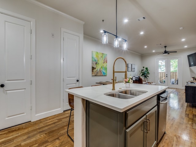 kitchen with french doors, a center island with sink, sink, crown molding, and light hardwood / wood-style floors