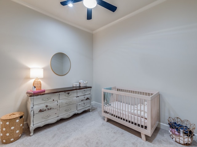 bedroom with light colored carpet, crown molding, a crib, and ceiling fan