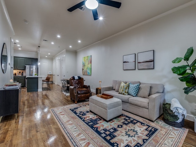 living room with crown molding, dark wood-type flooring, and ceiling fan