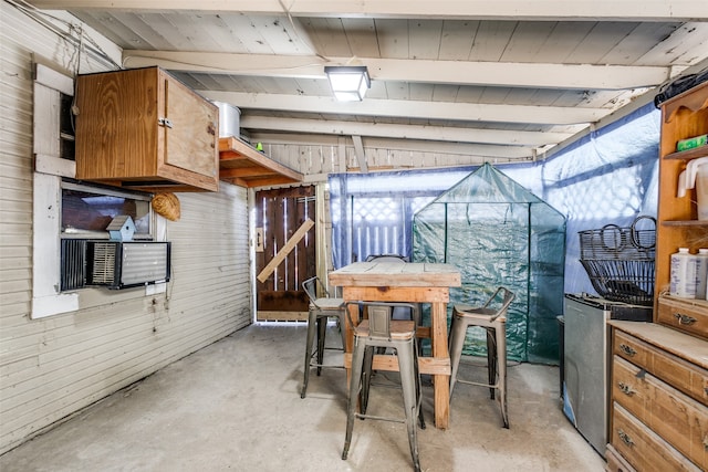 interior space featuring wooden walls and lofted ceiling with beams