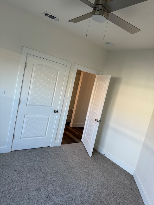 unfurnished bedroom featuring a closet, dark carpet, and ceiling fan