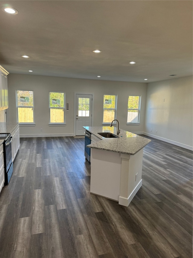 kitchen with a center island with sink, sink, white cabinetry, stainless steel appliances, and dark hardwood / wood-style floors