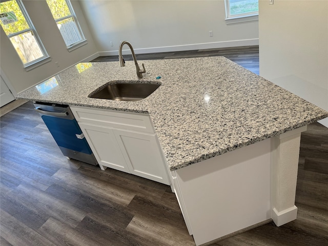 kitchen with white cabinets, an island with sink, light stone countertops, dark hardwood / wood-style floors, and sink