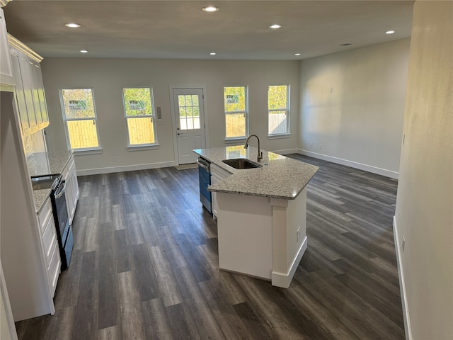 kitchen featuring sink, stainless steel appliances, white cabinets, dark wood-type flooring, and a center island with sink