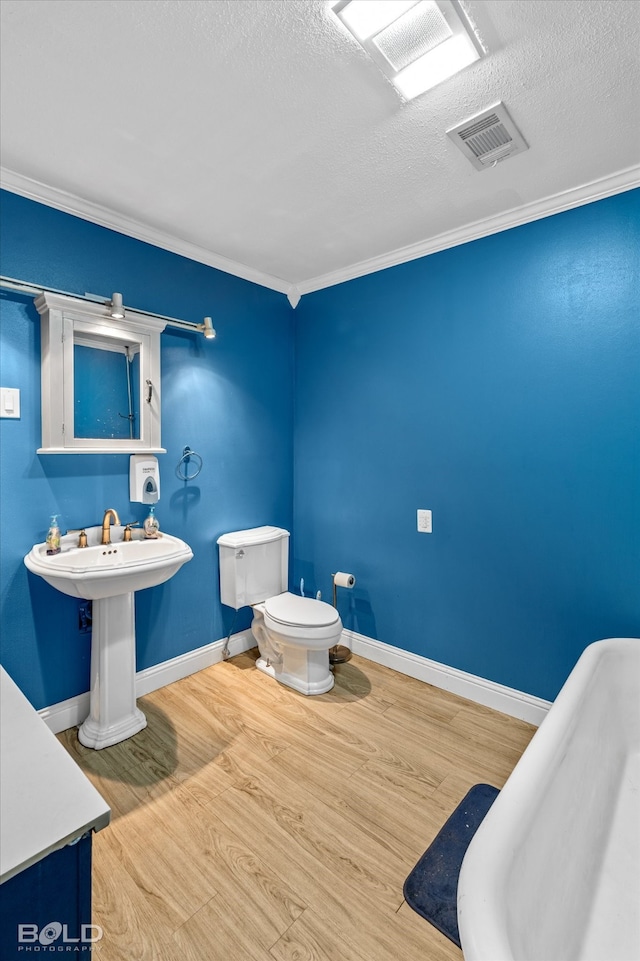 bathroom with a bathtub, toilet, hardwood / wood-style flooring, and ornamental molding