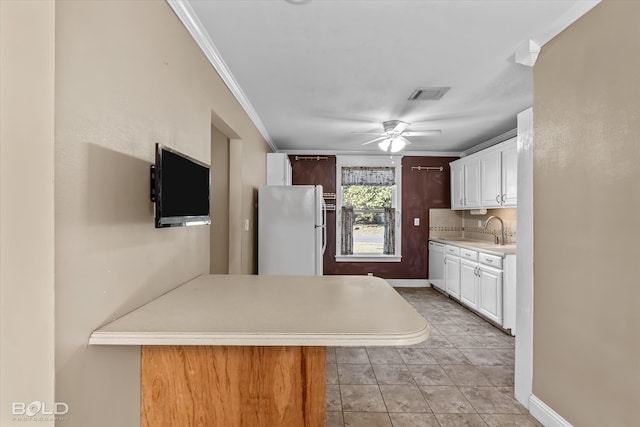 kitchen with decorative backsplash, ornamental molding, sink, white cabinetry, and white fridge