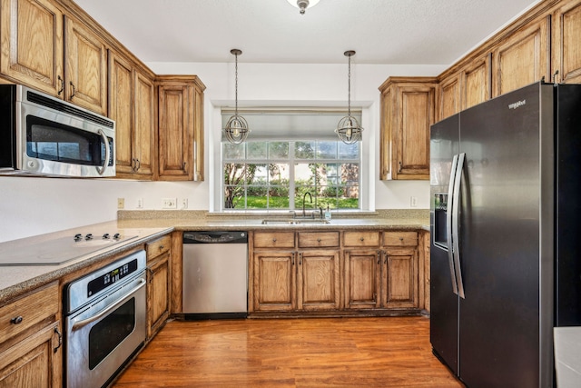 kitchen featuring dark hardwood / wood-style flooring, sink, hanging light fixtures, and appliances with stainless steel finishes