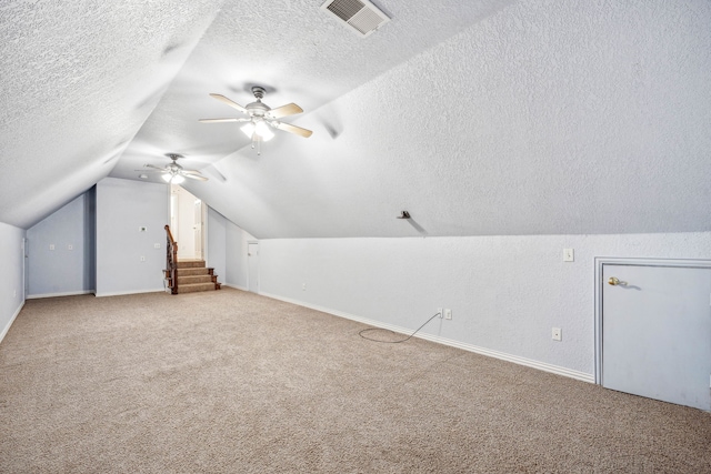 additional living space with lofted ceiling, carpet flooring, a textured ceiling, and ceiling fan