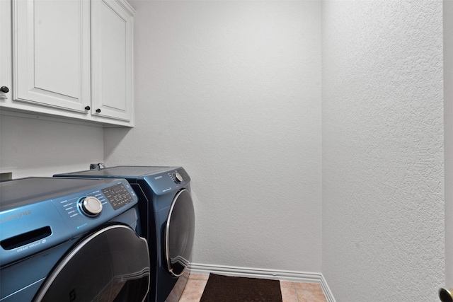 laundry room with cabinets, light tile patterned floors, and separate washer and dryer