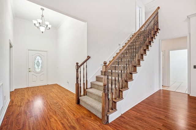 entryway featuring a chandelier, a high ceiling, hardwood / wood-style flooring, and crown molding