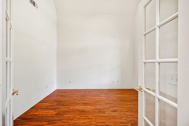unfurnished room with baseboards, wood finished floors, and visible vents