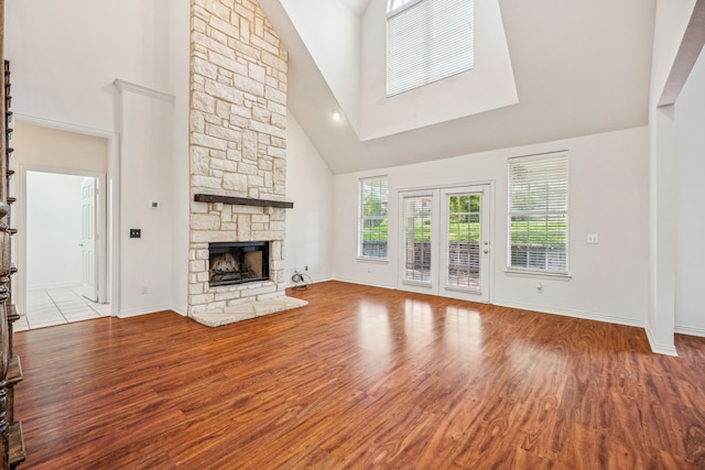 unfurnished living room featuring a fireplace, light hardwood / wood-style floors, and high vaulted ceiling