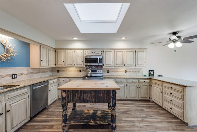 kitchen with hardwood / wood-style flooring, stainless steel appliances, backsplash, and light stone countertops