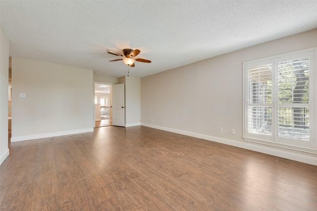 empty room with a textured ceiling, ceiling fan, and dark hardwood / wood-style flooring