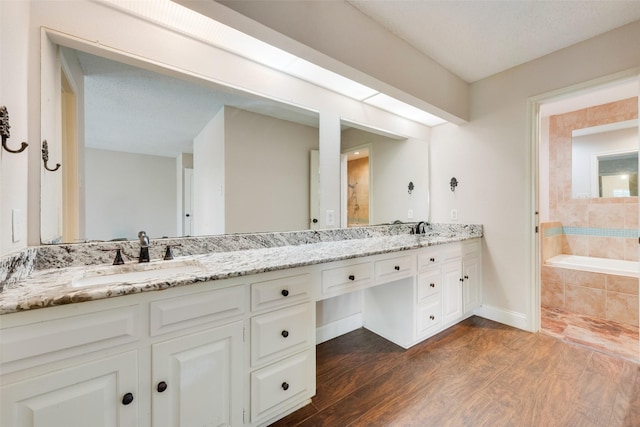 bathroom featuring tiled bath, hardwood / wood-style floors, and vanity