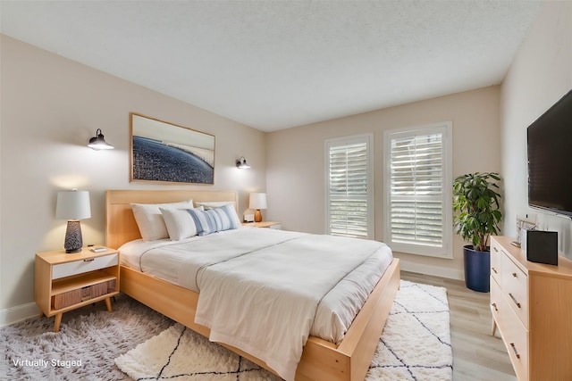 bedroom with light wood-type flooring and a textured ceiling