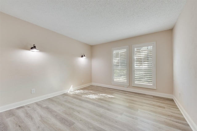 empty room with a textured ceiling and light hardwood / wood-style floors