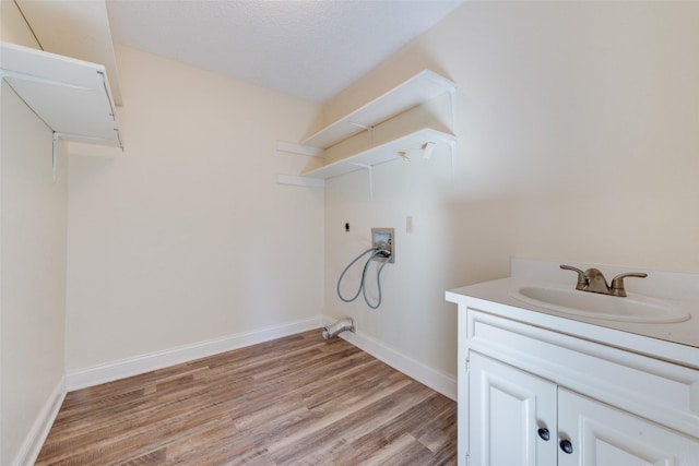 laundry room with a textured ceiling, light hardwood / wood-style floors, sink, hookup for a washing machine, and hookup for an electric dryer