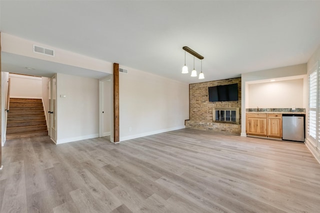 unfurnished living room featuring a fireplace, sink, and light hardwood / wood-style floors