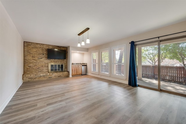 unfurnished living room with a brick fireplace and light hardwood / wood-style flooring