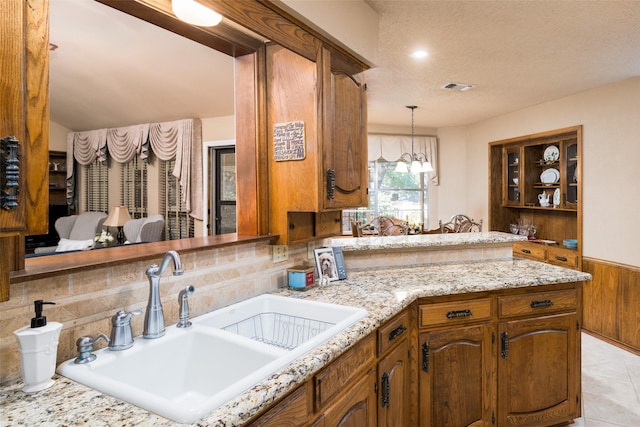 kitchen with wood walls, sink, light tile patterned floors, a textured ceiling, and a chandelier