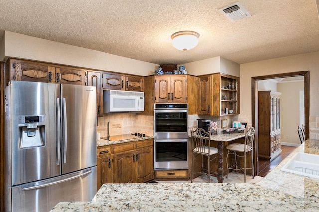 kitchen with backsplash, a textured ceiling, and appliances with stainless steel finishes