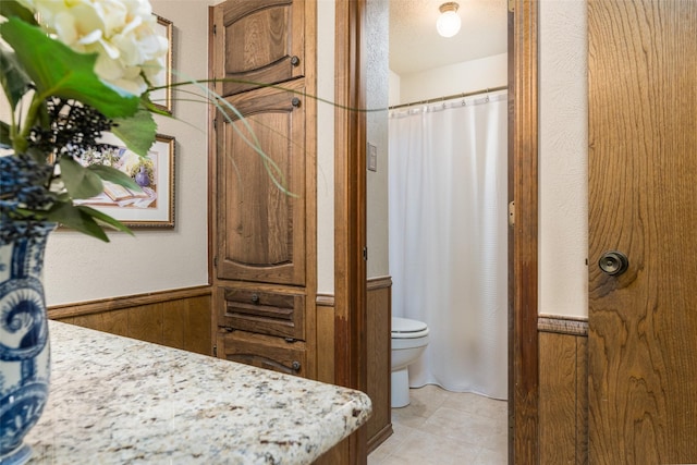 bathroom featuring wood walls, vanity, a textured ceiling, and toilet