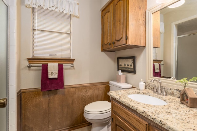 bathroom with vanity, toilet, walk in shower, and wood walls