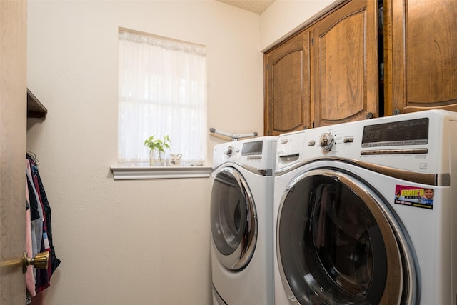 washroom with washing machine and dryer, a wealth of natural light, and cabinets